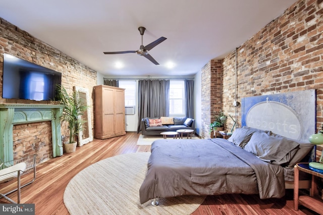 bedroom featuring brick wall and wood finished floors