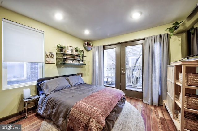 bedroom featuring french doors, multiple windows, and wood finished floors