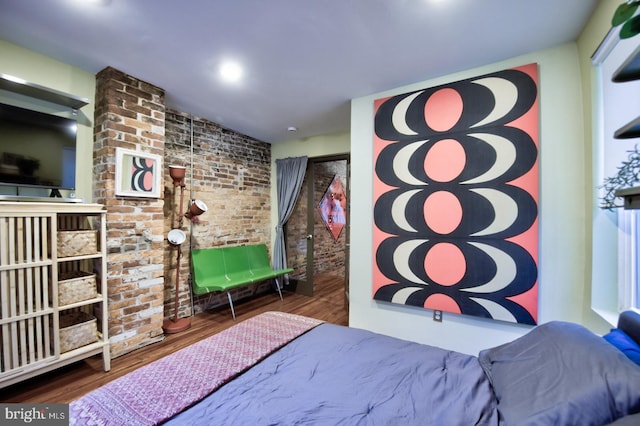 bedroom featuring dark wood finished floors and brick wall