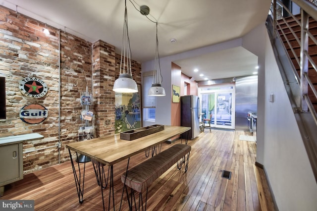 dining space featuring brick wall and light wood-type flooring