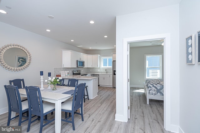 dining space with light hardwood / wood-style floors, ceiling fan, and sink