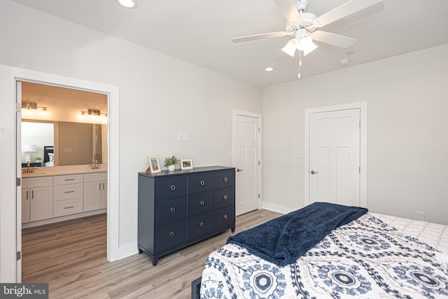 bedroom with light wood-type flooring, ensuite bath, ceiling fan, and sink