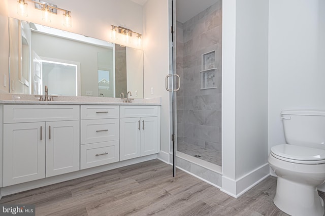 bathroom with hardwood / wood-style floors, vanity, an enclosed shower, and toilet