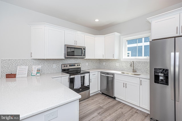 kitchen with white cabinetry, sink, stainless steel appliances, and light hardwood / wood-style floors