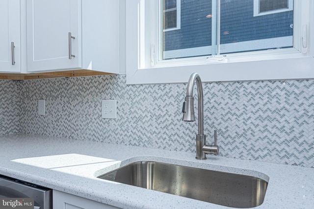 room details with white cabinetry, sink, and light stone counters