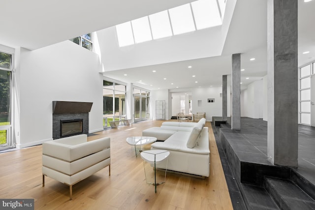 living room with a towering ceiling, light wood-style floors, a fireplace, and recessed lighting