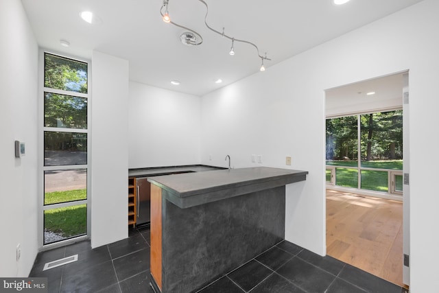 bar with a wealth of natural light, dark tile patterned floors, and recessed lighting