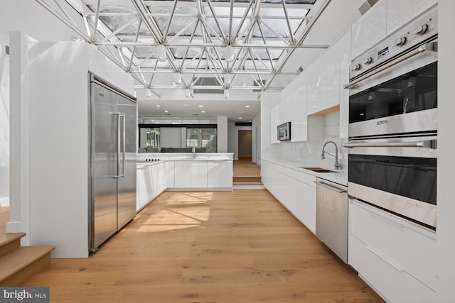 kitchen featuring modern cabinets, appliances with stainless steel finishes, white cabinets, and a sink