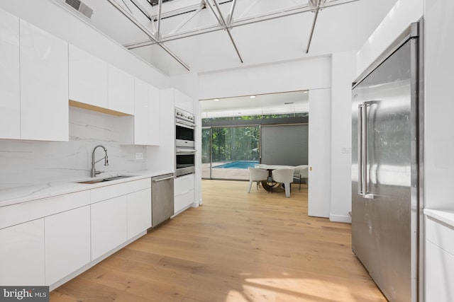 kitchen featuring appliances with stainless steel finishes, modern cabinets, a sink, and white cabinetry