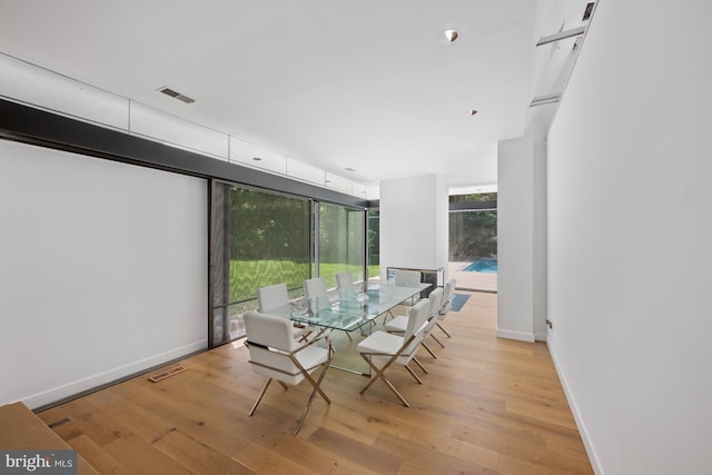 dining area featuring light wood finished floors, baseboards, expansive windows, and visible vents