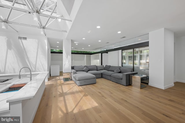 living room with light wood-type flooring, visible vents, baseboards, and recessed lighting