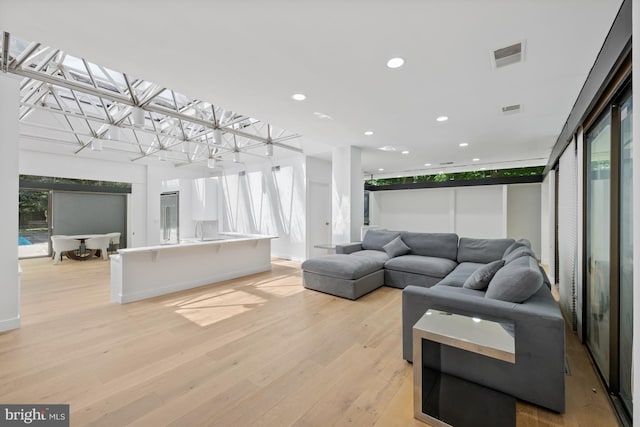 living area featuring light wood-style floors, a wealth of natural light, and visible vents