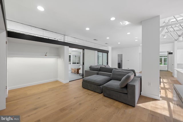 living room featuring light wood-style floors, visible vents, baseboards, and recessed lighting