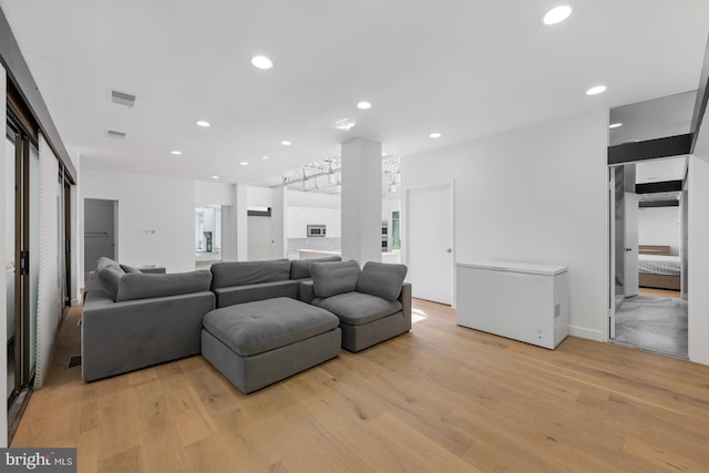 living room featuring light wood-type flooring, visible vents, and recessed lighting