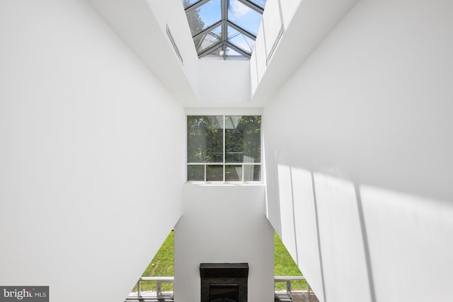 staircase with a wealth of natural light, a skylight, a fireplace, and a towering ceiling