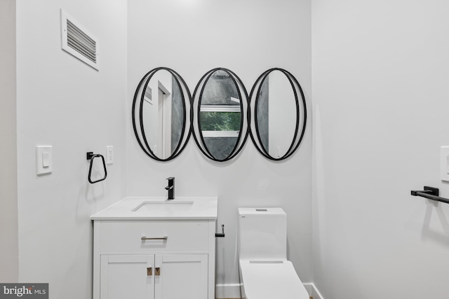 half bath featuring visible vents, vanity, and toilet