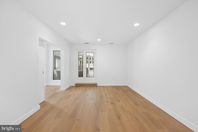 spare room featuring light wood finished floors, recessed lighting, and baseboards