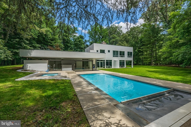 rear view of property featuring a patio, stucco siding, a lawn, a hot tub, and an outdoor pool