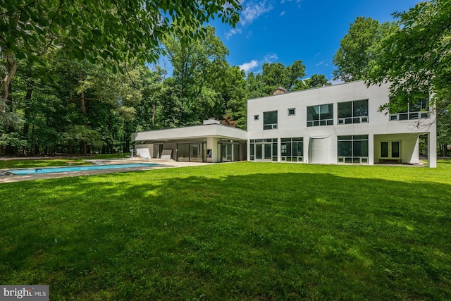 rear view of house featuring an attached carport, an outdoor pool, a yard, and a chimney