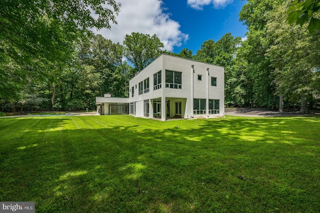 back of property featuring a yard and stucco siding