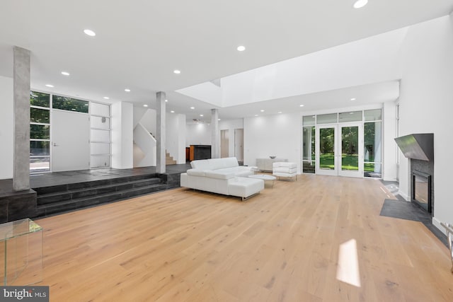 living room featuring stairway, wood finished floors, french doors, a fireplace, and recessed lighting