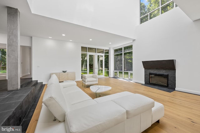 living room with a fireplace with flush hearth, plenty of natural light, baseboards, and wood finished floors