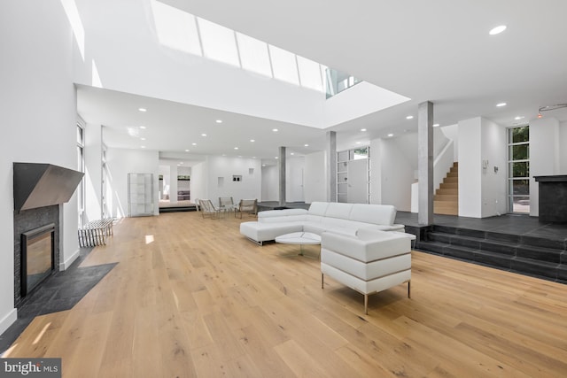 living area featuring wood finished floors, stairway, a fireplace with flush hearth, and recessed lighting