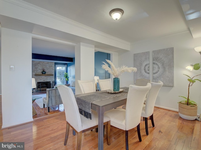 dining space featuring hardwood / wood-style floors, a large fireplace, and crown molding