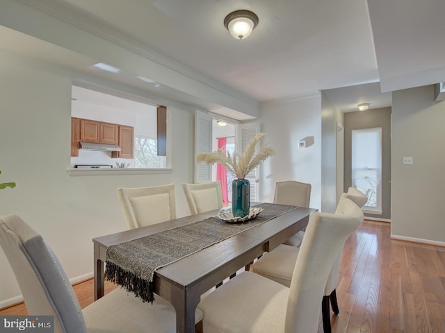 dining space with crown molding and light hardwood / wood-style flooring