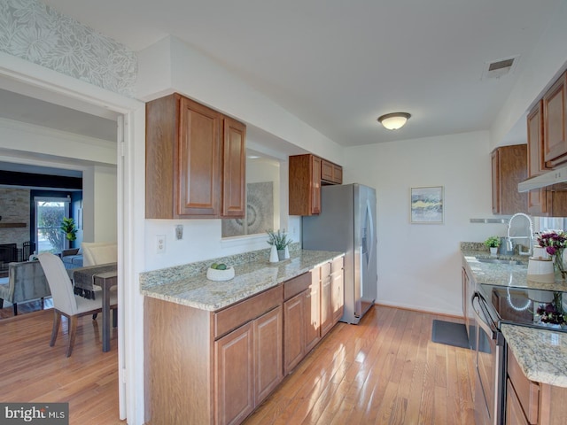 kitchen with light stone counters, light hardwood / wood-style flooring, stainless steel appliances, and sink