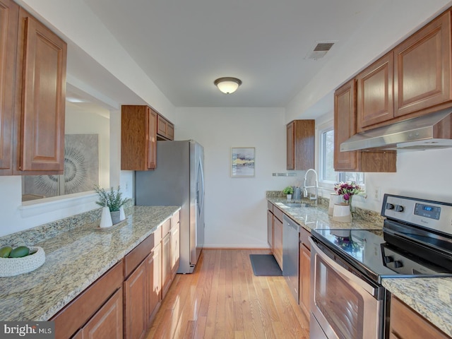 kitchen featuring sink, light wood-type flooring, light stone countertops, range hood, and stainless steel appliances