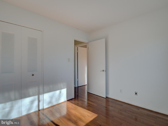 unfurnished bedroom featuring dark hardwood / wood-style flooring and a closet