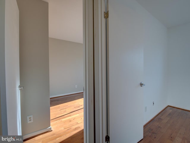 corridor with hardwood / wood-style floors and vaulted ceiling