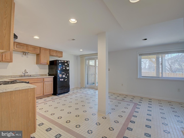 kitchen with sink, black refrigerator, and light brown cabinets