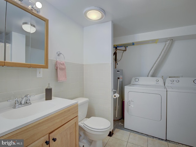 bathroom featuring tile patterned floors, vanity, tile walls, washing machine and dryer, and toilet