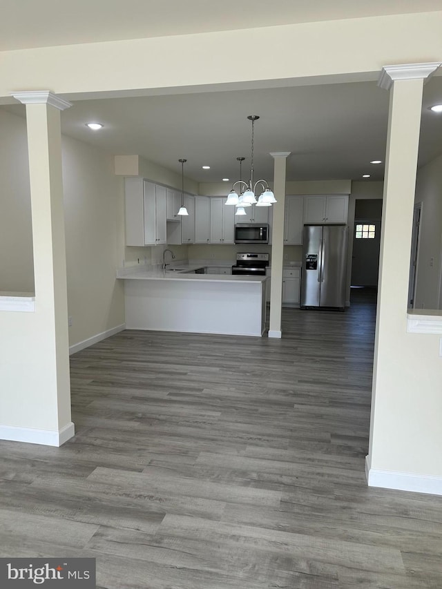 kitchen with kitchen peninsula, hanging light fixtures, stainless steel appliances, and light wood-type flooring