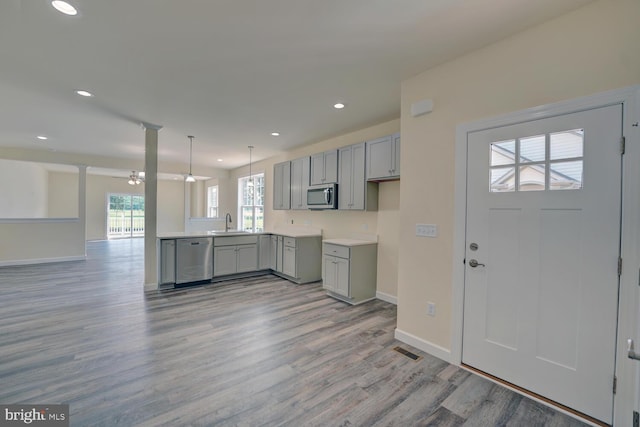 kitchen featuring pendant lighting, gray cabinetry, sink, light hardwood / wood-style flooring, and stainless steel appliances