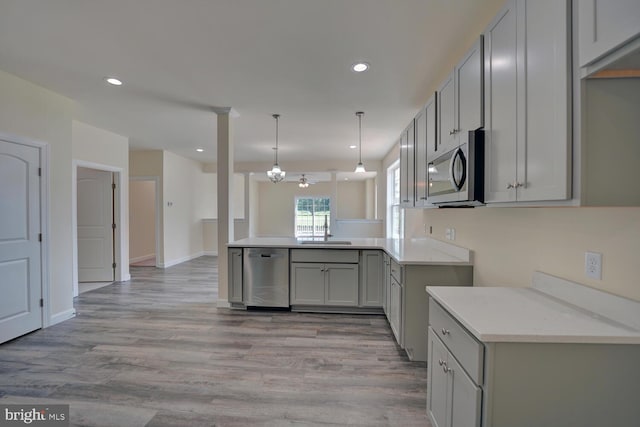 kitchen with kitchen peninsula, light wood-type flooring, gray cabinetry, stainless steel appliances, and ceiling fan