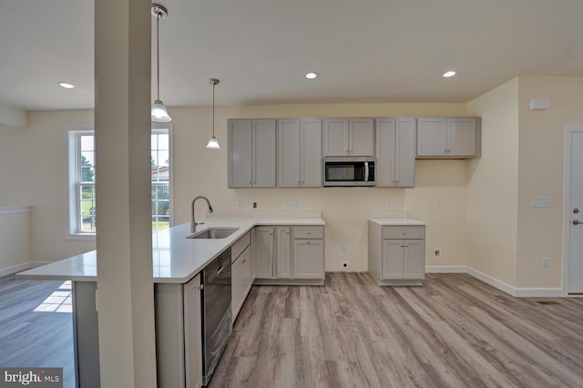 kitchen featuring gray cabinetry, hanging light fixtures, sink, light wood-type flooring, and appliances with stainless steel finishes