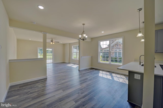 interior space with gray cabinetry, pendant lighting, dark wood-type flooring, and ceiling fan with notable chandelier