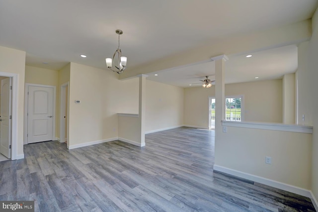 empty room with ceiling fan with notable chandelier and light wood-type flooring