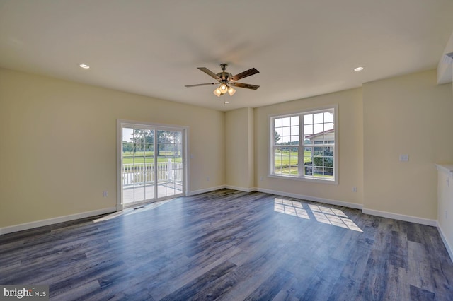 spare room with a wealth of natural light, ceiling fan, and dark wood-type flooring