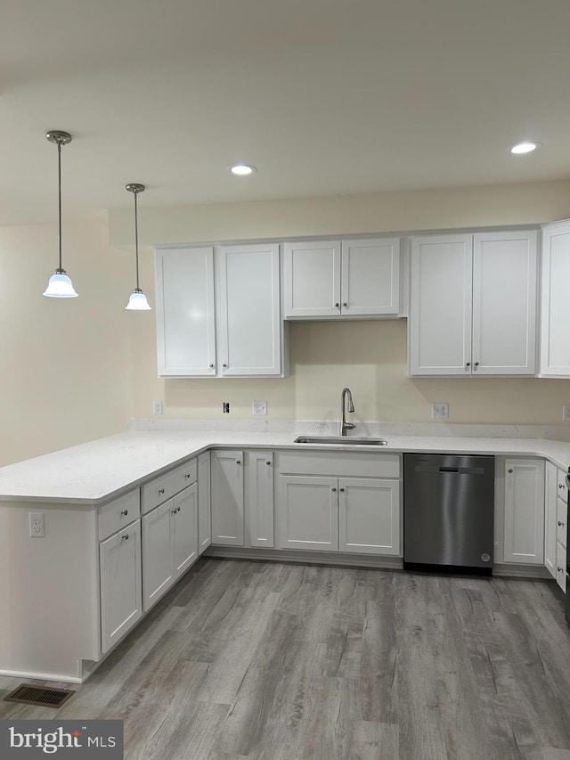 kitchen featuring white cabinetry, sink, stainless steel dishwasher, light hardwood / wood-style floors, and decorative light fixtures