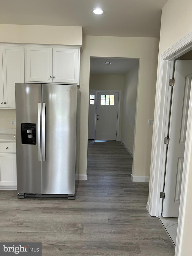 kitchen featuring white cabinets, stainless steel refrigerator with ice dispenser, and wood-type flooring