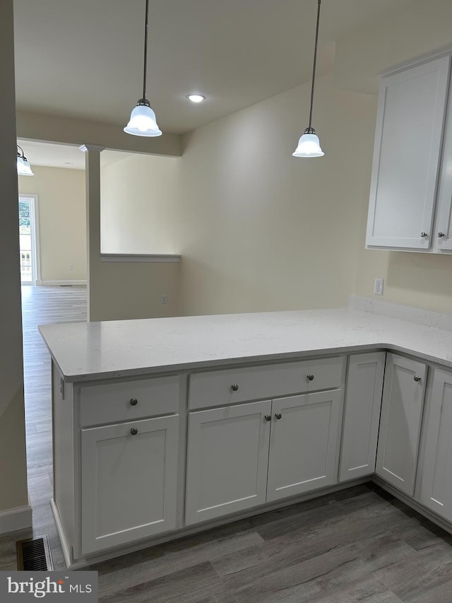 kitchen featuring light stone countertops, white cabinetry, dark hardwood / wood-style flooring, and hanging light fixtures