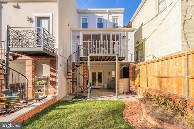 rear view of house featuring ceiling fan, a yard, a balcony, and a patio