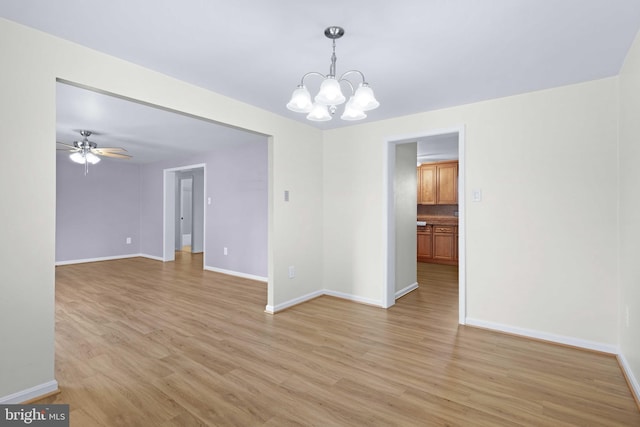 spare room with ceiling fan with notable chandelier and light hardwood / wood-style flooring