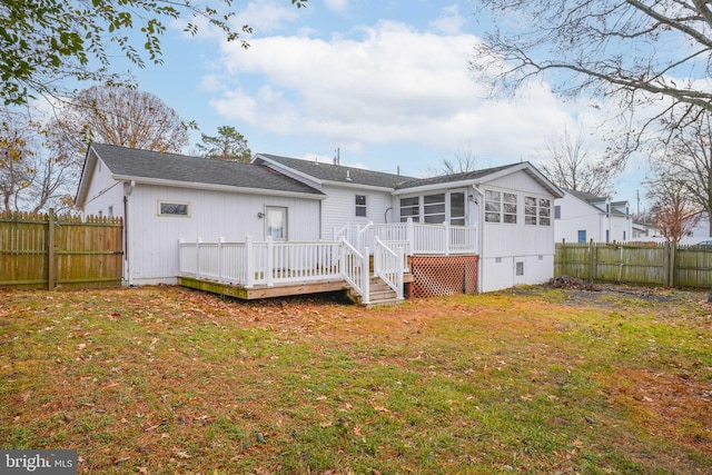 rear view of house featuring a deck, a yard, and a sunroom