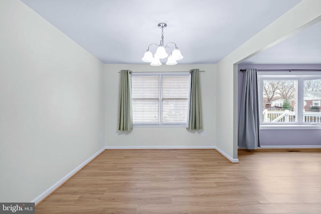 empty room featuring an inviting chandelier and light wood-type flooring