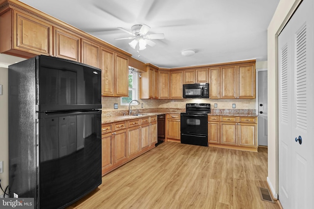 kitchen featuring light stone countertops, black appliances, light wood-type flooring, ceiling fan, and sink